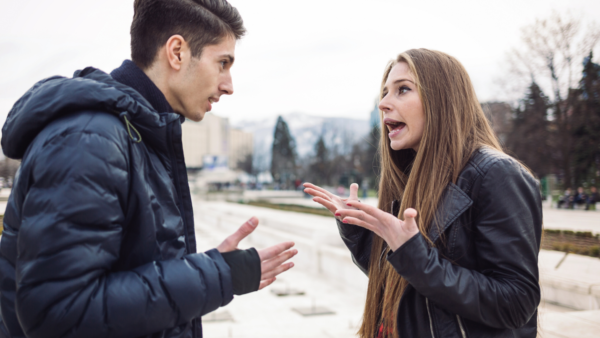 A man and woman argue on a public sidewalk.