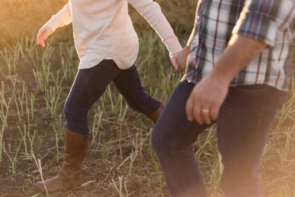 two people holding hands and walking in a field