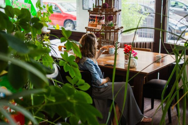 Woman sitting at wooden table amongst green plants