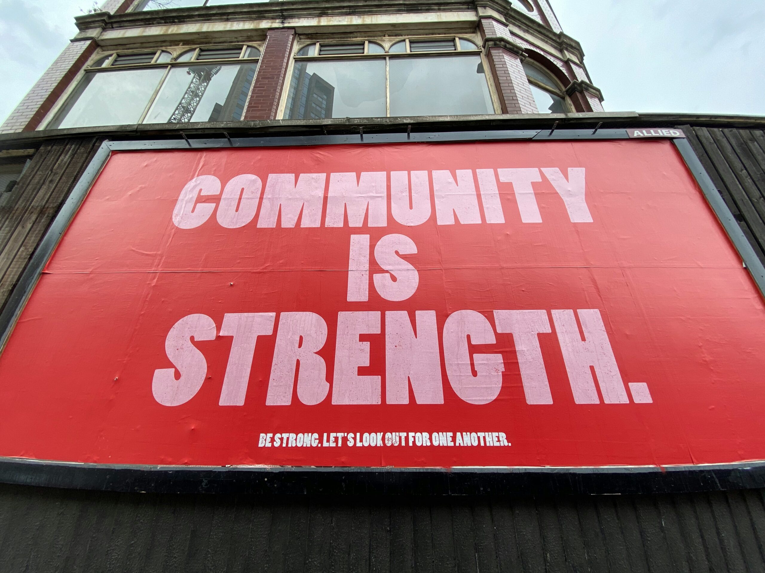 Large red sign saying Community is Strength