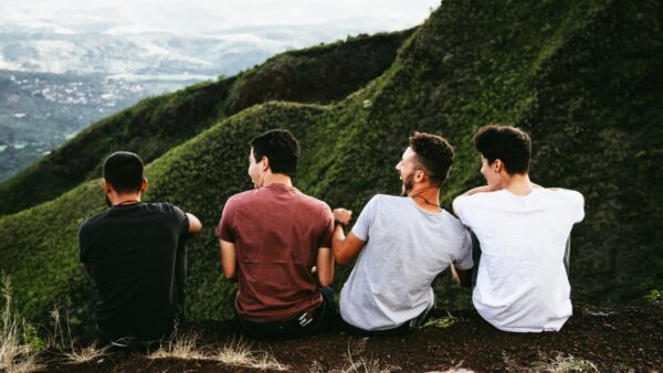 A group of men sit together at the top of a mountain after a hike.