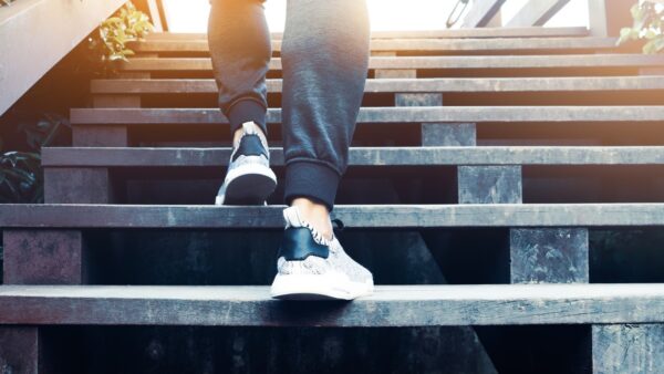 A woman wearing athletic clothes walks up a set of wooden stairs.