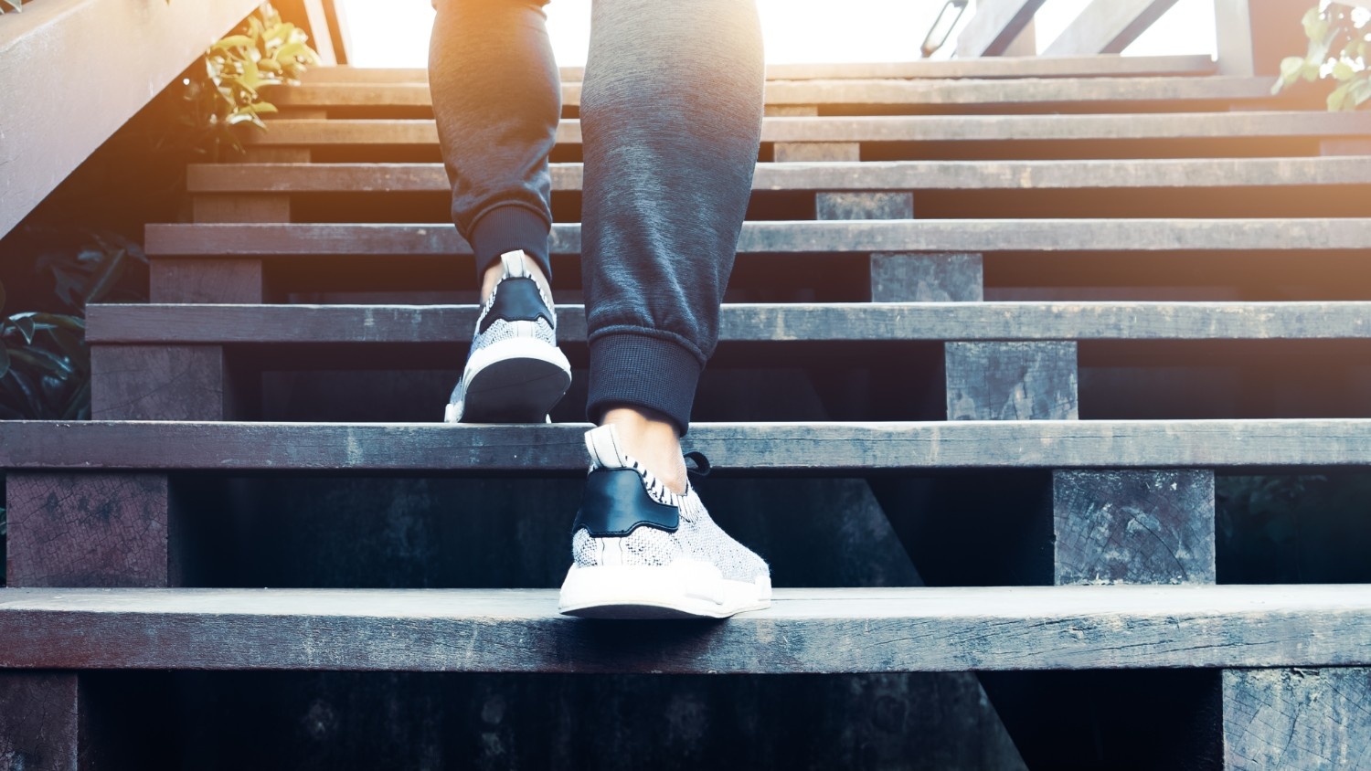 A woman wearing athletic clothes walks up a set of wooden stairs.