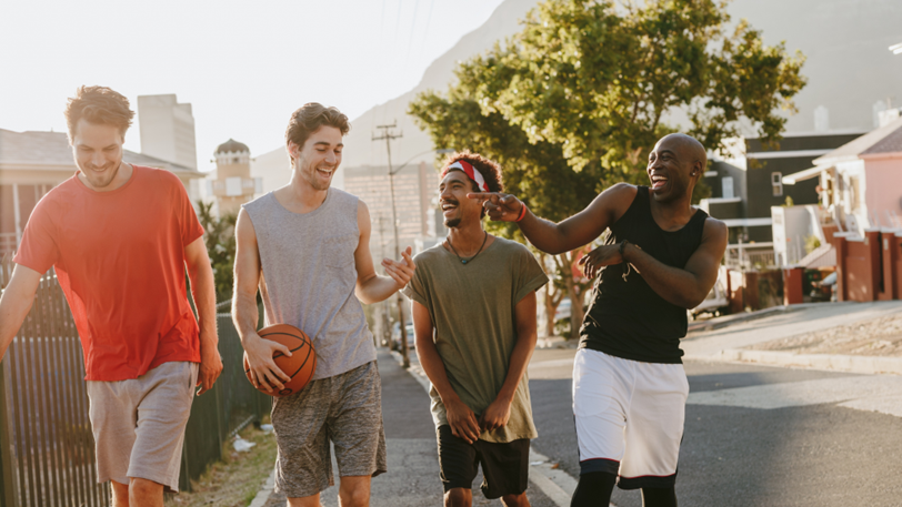 A group of guys in athletic wear walk home after a game of basketball.